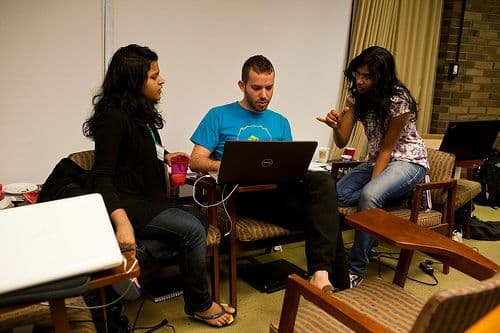 People sitting and discussing around a computer.