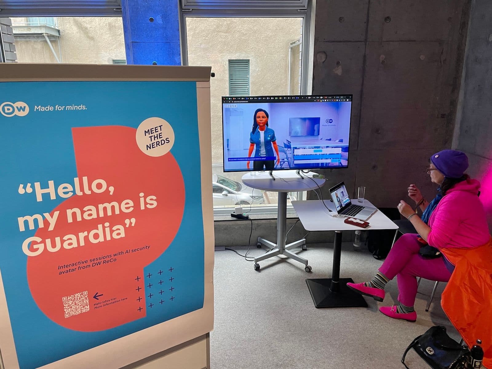 Photo of a test session. Foreground: Guardia poster. Background: A DW colleague testing the system on a laptop and a big screen.