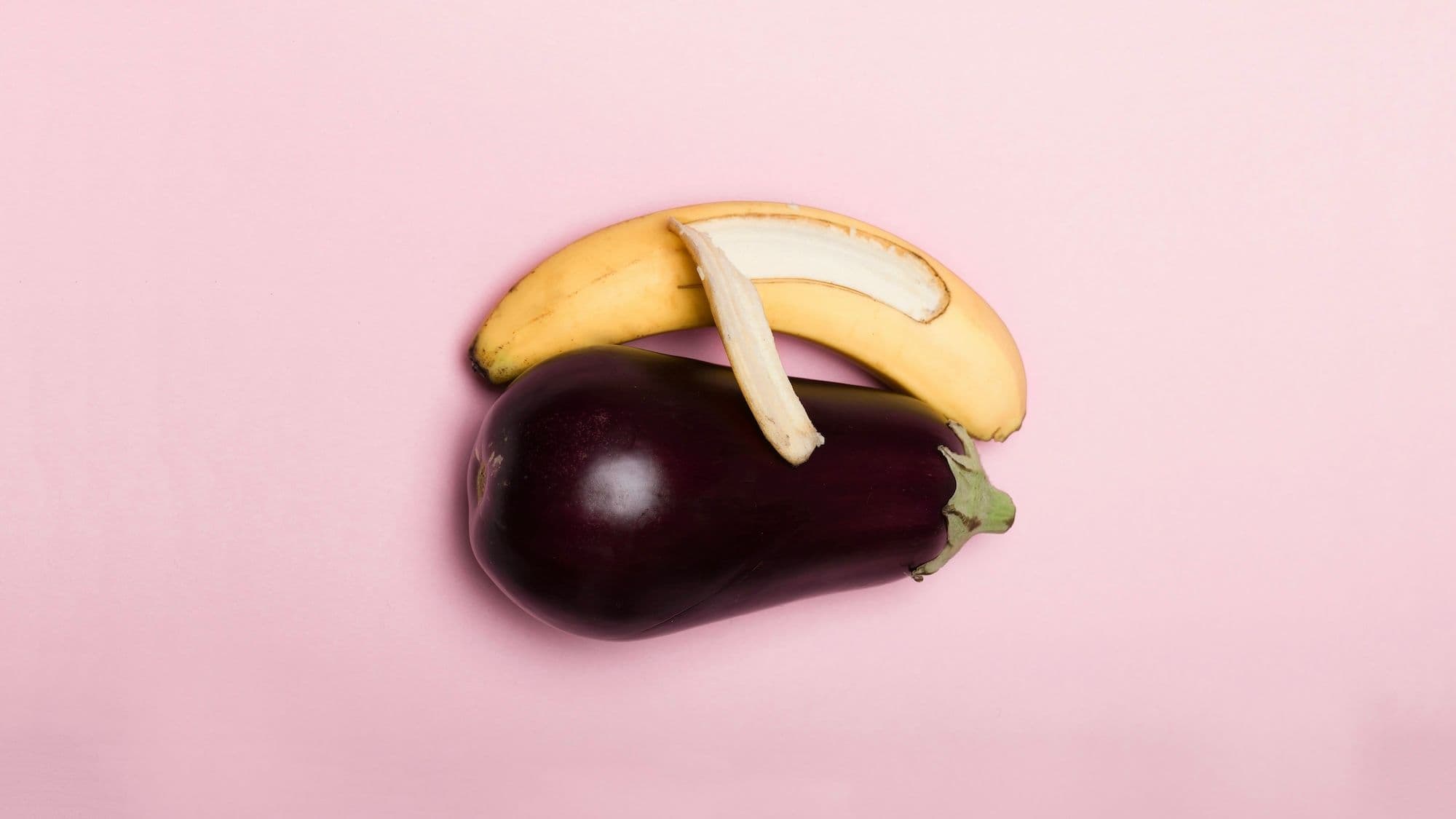 Photo of a half-peeled banana lying next to and "hugging" an eggplant. Via Deon Black on Unsplash.