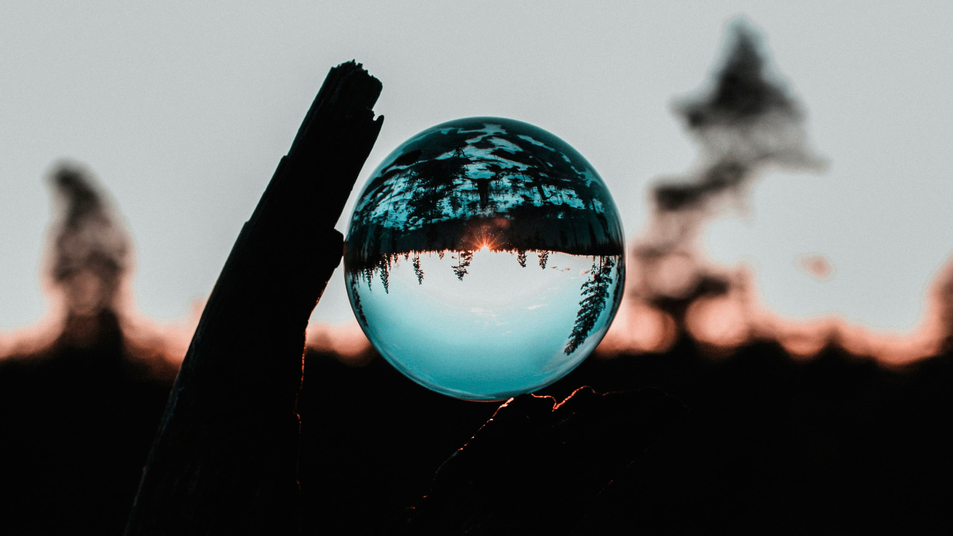 An upside-down crystal ball, mirroring landscape with trees and blue sky.