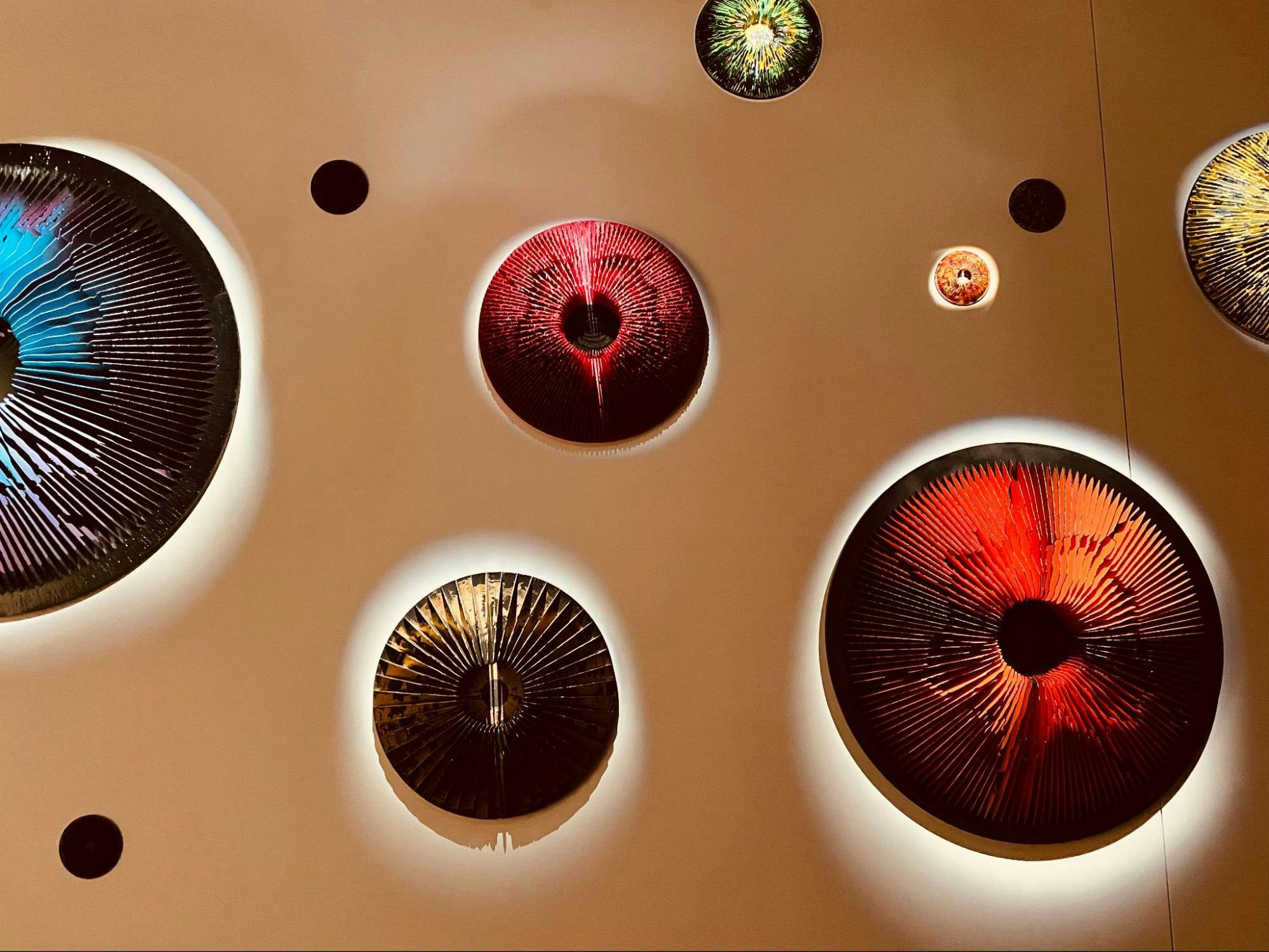 Picture shows a part of Vasily Klyukin’s ‘Mindspace’ installation: Multi-colored, structured, and portal-like spherical caps attached to a wall.